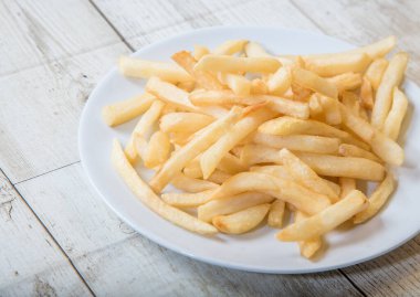 Ahşap tabakta beyaz bir tabakta patates kızartması, barbekü sosu, domates sosu.