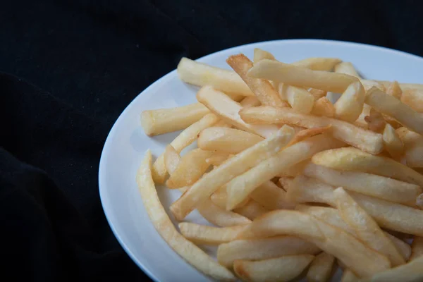 Ahşap tabakta beyaz bir tabakta patates kızartması, barbekü sosu, domates sosu.
