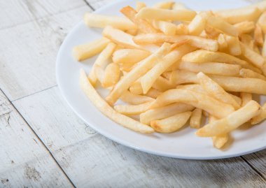 Ahşap tabakta beyaz bir tabakta patates kızartması, barbekü sosu, domates sosu.