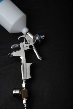 Endüstriyel boya ve kaplama için kullanılan ve siyah arka planda izole edilmiş endüstriyel boyalı sprey tabancayı tutan ressamın el resmi.