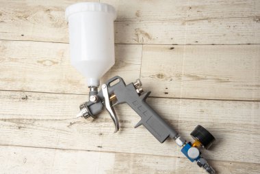 Endüstriyel boya ve kaplama için kullanılan ve siyah arka planda izole edilmiş endüstriyel boyalı sprey tabancayı tutan ressamın el resmi.