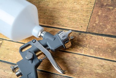 Endüstriyel boya ve kaplama için kullanılan ve siyah arka planda izole edilmiş endüstriyel boyalı sprey tabancayı tutan ressamın el resmi.