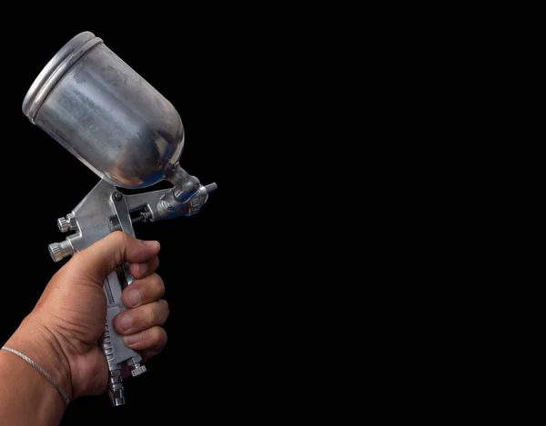 Hand holding paint spray gun Paint spray on floors Image of the painter\'s arm hand holding industrial size spray gun used for industrial painting and coating and isolated on background clipingpart