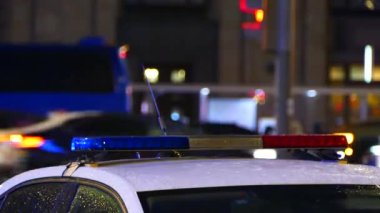 Polis arabasındaki polis ışıkları geceleri yanıp sönüyor, arka planda yoğun trafik var.