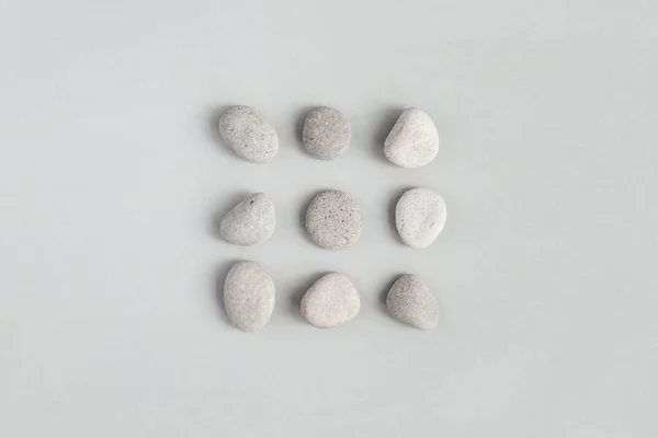 Pebble stones on light gray background, minimal design flat lay