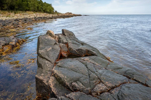 Ein Fels gegen blaues Wasser. Bild aus Skalderviken, Schweden — Stockfoto