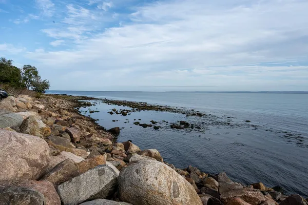 A rocky shoreline with blue water and a blu sky in the background. Picture from Skalderviken, Sweden — Stock Photo, Image