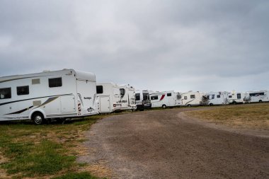 Arka planda dramatik bir gökyüzü olan kamp minibüsleri