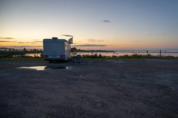 Güzel gün batımı ışığında okyanus kıyısında park etmiş bir karavan.
