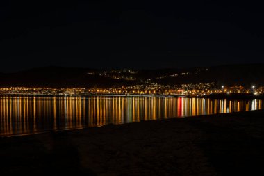 Kasaba ışıkları gece bir gölde yankılanıyor.