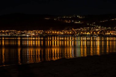Yamaçtaki bir kasabadan gelen ışıklar geceleri bir göle yansıyor.