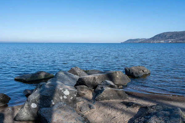 Boulders as a part of a wave breaker in a lake. Picture from Lake Vattern, Sweden. Blue water and sky in the background