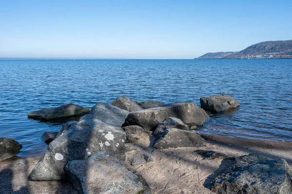 Boulders as a part of a wave breaker in a lake. Picture from Lake Vattern, Sweden. Blue water and sky in the background