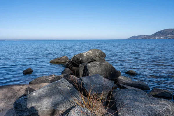Boulders as a part of a wave breaker in a lake. Picture from Lake Vattern, Sweden. Blue water and sky in the background