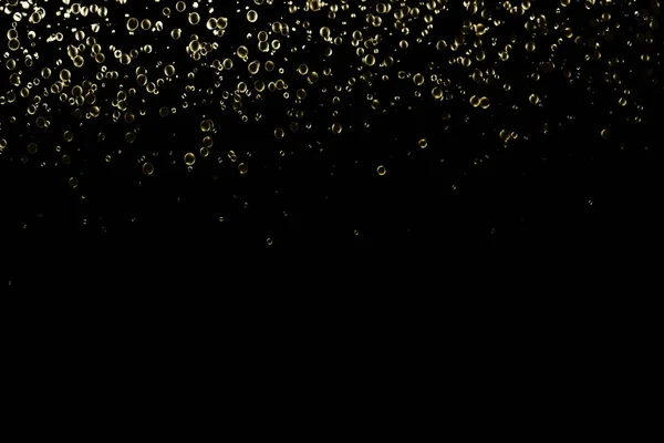 黒色に孤立した金色の円状粒子が輝く背景 — ストック写真