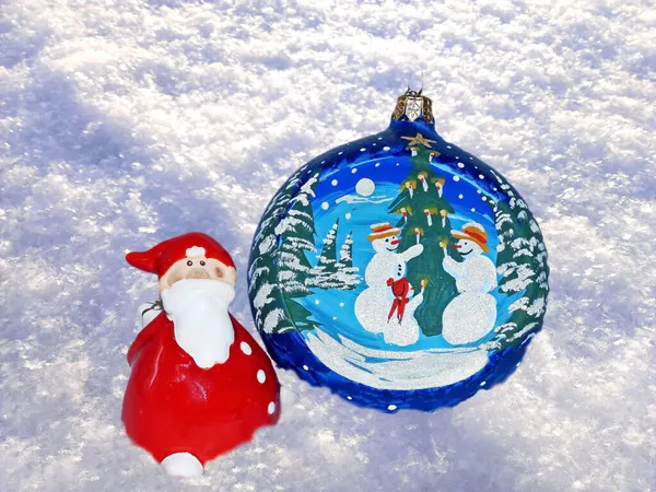Noel Baba, beyaz kar üzerinde cam bir topla yeni yıla doğru koşuyor. Yeni yıl oyuncakları. Şenlik arka planı. Yeni Yıl ve Noel