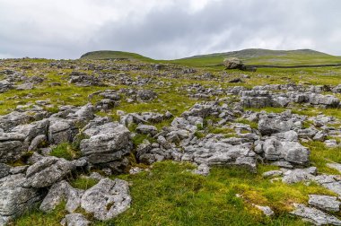Ingleborough, Yorkshire, İngiltere 'nin güney yamaçlarındaki buzul erratiklerine doğru kireçtaşı kaldırım manzarası
