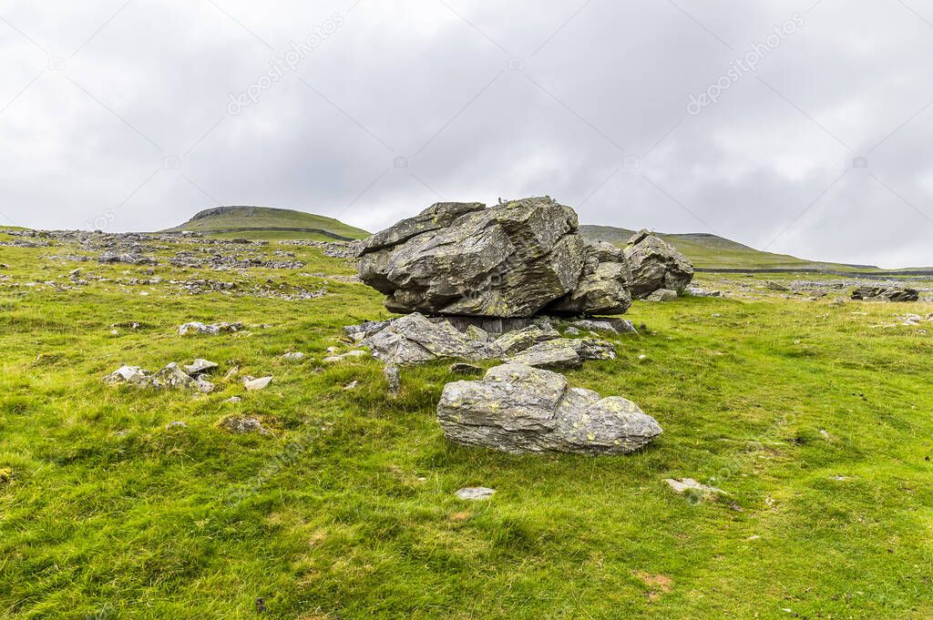 A view of a glacial erratics deposited on limestone bases on the southern slopes of Ingleborough, Yorkshire, UK in summertime
