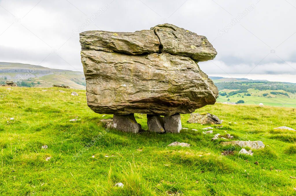 A side view of a glacial erratic supported on the limestone pavement on the southern slopes of Ingleborough, Yorkshire, UK in summertime