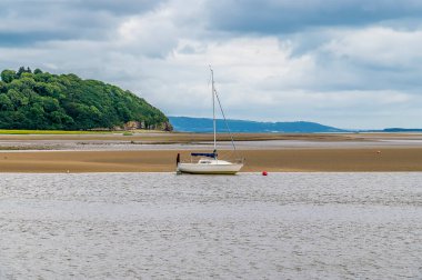 Laugharne, Pembrokeshire, Güney Galler 'de bir yaz günü, alçak gelgitte Taf nehrinde bir tekne manzarası.