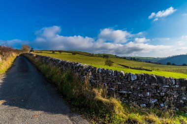 Güneşli bir sonbahar gününde İngiltere 'nin Wetton köyünün etrafındaki kuru taş duvarlar arasından bir manzara