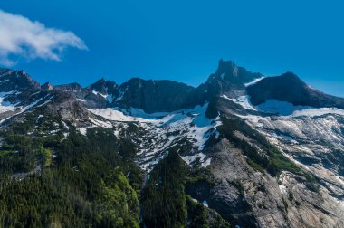 An aerial view of snow covered mountain peaks above Skagway, Alaska in summertime