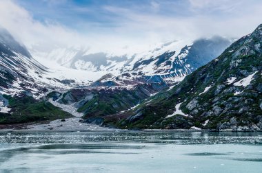 A view of snow flowing down a valley in Glacier Bay, Alaska in summertime
