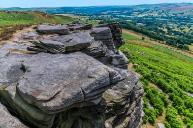 A view of rock strata and large slabs of Gritstone on the top of the Bamford Edge, UK in summertime