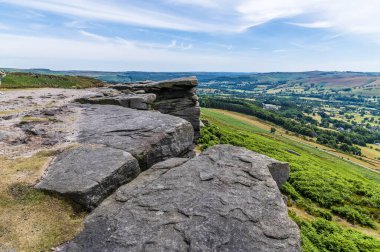 A view past rock slabs on the top of Bamford Edge, UK in summertime
