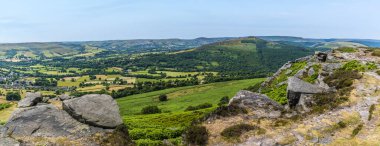 A panorama view past rock slabs on the top of Bamford Edge, UK in summertime
