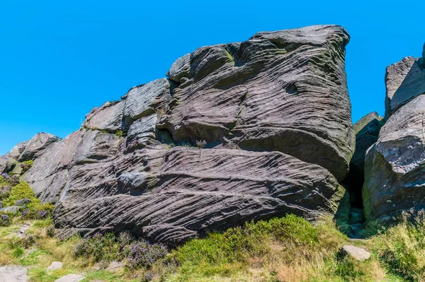 A view of a wind eroded rock beside the path on the summit of the Roaches escarpment, Staffordshire, UK in summertime