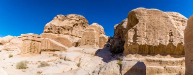 Yazın Ürdün 'ün antik kenti Petra' ya giden yolun yanındaki eski kaya yapılarının manzarası.