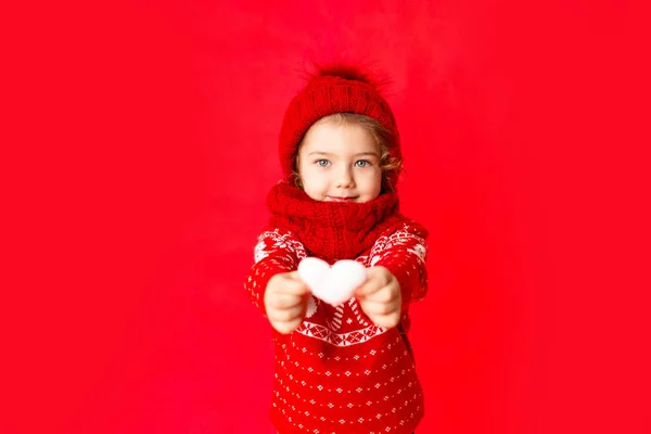 Gyermek Egy Kislány Téli Ruhában Szívet Tart Piros Háttéren Szilveszteri — Stock Fotó