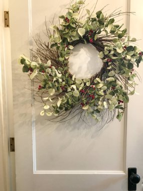 Kapıda süslü bir Noel çelengi var.