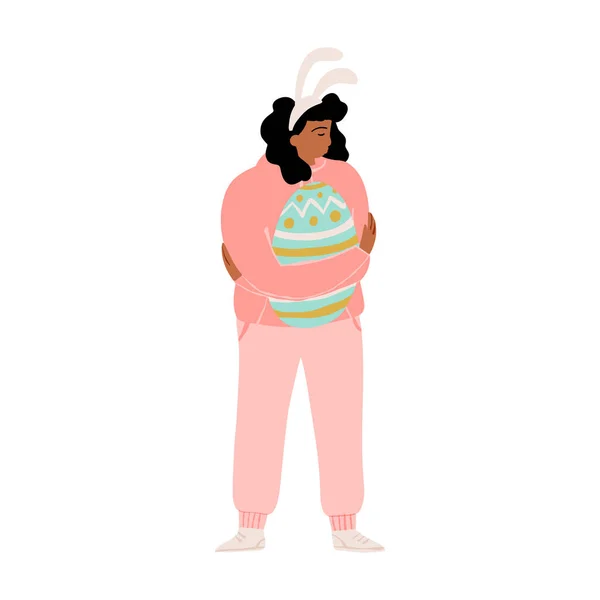 Милая девушка в повязке с кроличьими ушами, нежно обнимающая огромное украшенное пасхальное яйцо. Векторная иллюстрация пасхальных праздников. — стоковый вектор