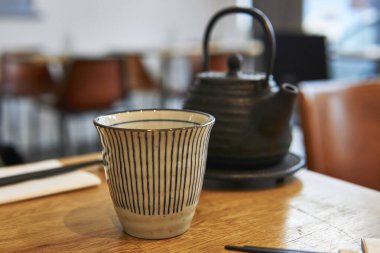 Restoran masasında Asya çaydanlığı ve fincanı. Siyah çaydanlık.