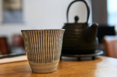 Restoran masasında Asya çaydanlığı ve fincanı. Siyah çaydanlık.