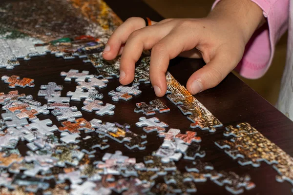 Little girl doing jigsaw puzzle at home. Close up photo with selective focus. — Stockfoto