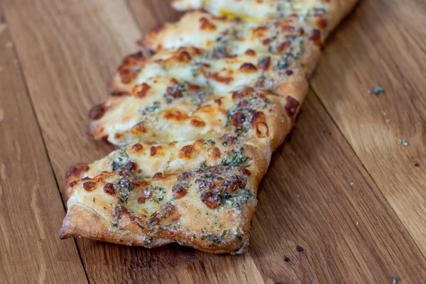 Toasted cheese and garlic bread. Italian cuisine. Sliced cheese garlic bread with white sauce on a wooden background.