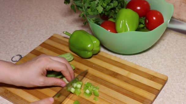 Zöld paprikát szeletelő kezek egy vágódeszkán. Zöldségek — Stock videók