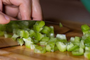 Tahtada taze yeşil biber kesiliyor, yakın plan.