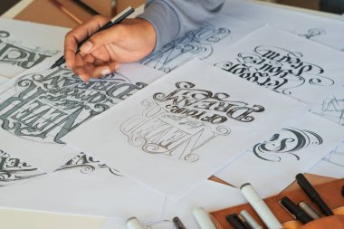 Tipografi Hattatçısı çizim çizimi yazarken imlâ edilen kalem fırçası mürekkep tablosu çizimlerine izin veriyor. İş yeri tasarım stüdyosu.