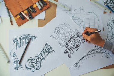 Typography Calligraphy artist designer drawing sketch writes letting spelled pen brush ink paper table artwork.Workplace design studio.