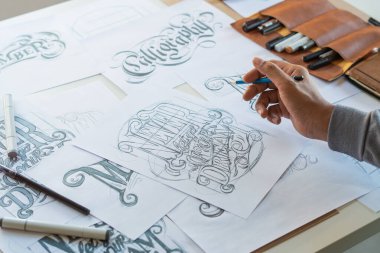 Tipografi Hattatçısı çizim çizimi yazarken imlâ edilen kalem fırçası mürekkep tablosu çizimlerine izin veriyor. İş yeri tasarım stüdyosu.