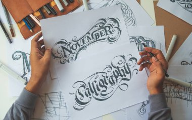 Tipografi Hattatçısı çizim çizimi yazarken imlâ edilen kalem fırçası mürekkep tablosu çizimlerine izin veriyor. İş yeri tasarım stüdyosu.