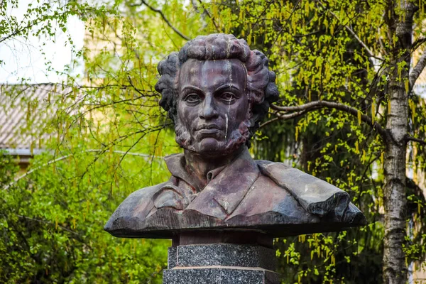 POLTAVA, UKRAINE - MAY 1, 2022: Bronze monument to the Russian poet Alexander Pushkin against the backdrop of green trees during the day