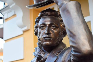 POLTAVA, UKRAINE - MAY 1, 2022: Bronze sculpture of Russian poet Alexander Pushkin on the background of flags during the day