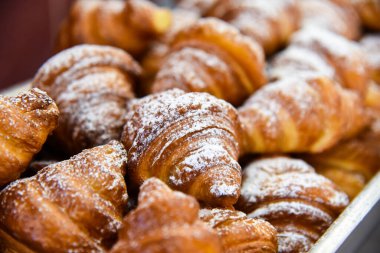 Taze pişmiş kruvasan üzerine şeker serpiştirilmiş.