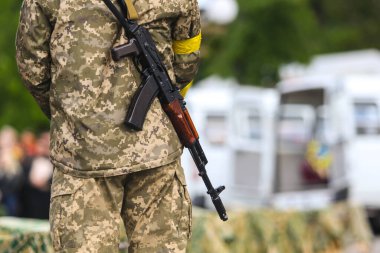 POLTAVA, UKRAINE  18 MAY, 2022: Ukrainian Territorial Defense Military with a yellow bandage and a Kalashnikov rifle