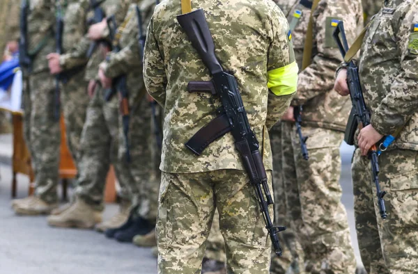 POLTAVA, UKRAINE  18 MAY, 2022: Ukrainian Territorial Defense Military with a yellow bandage and a Kalashnikov rifle